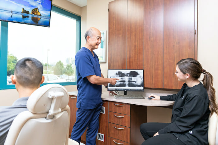 Dr. Sato and dental assistant discussing x-ray of patient's teeth