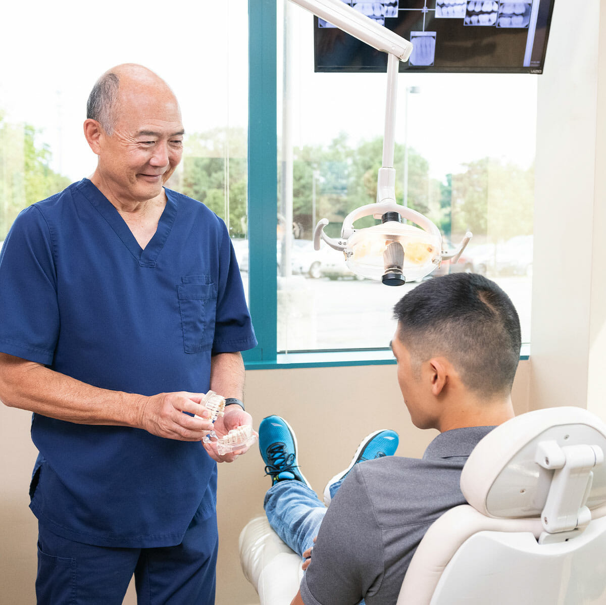 Dr. Sato showing patient a model of teeth