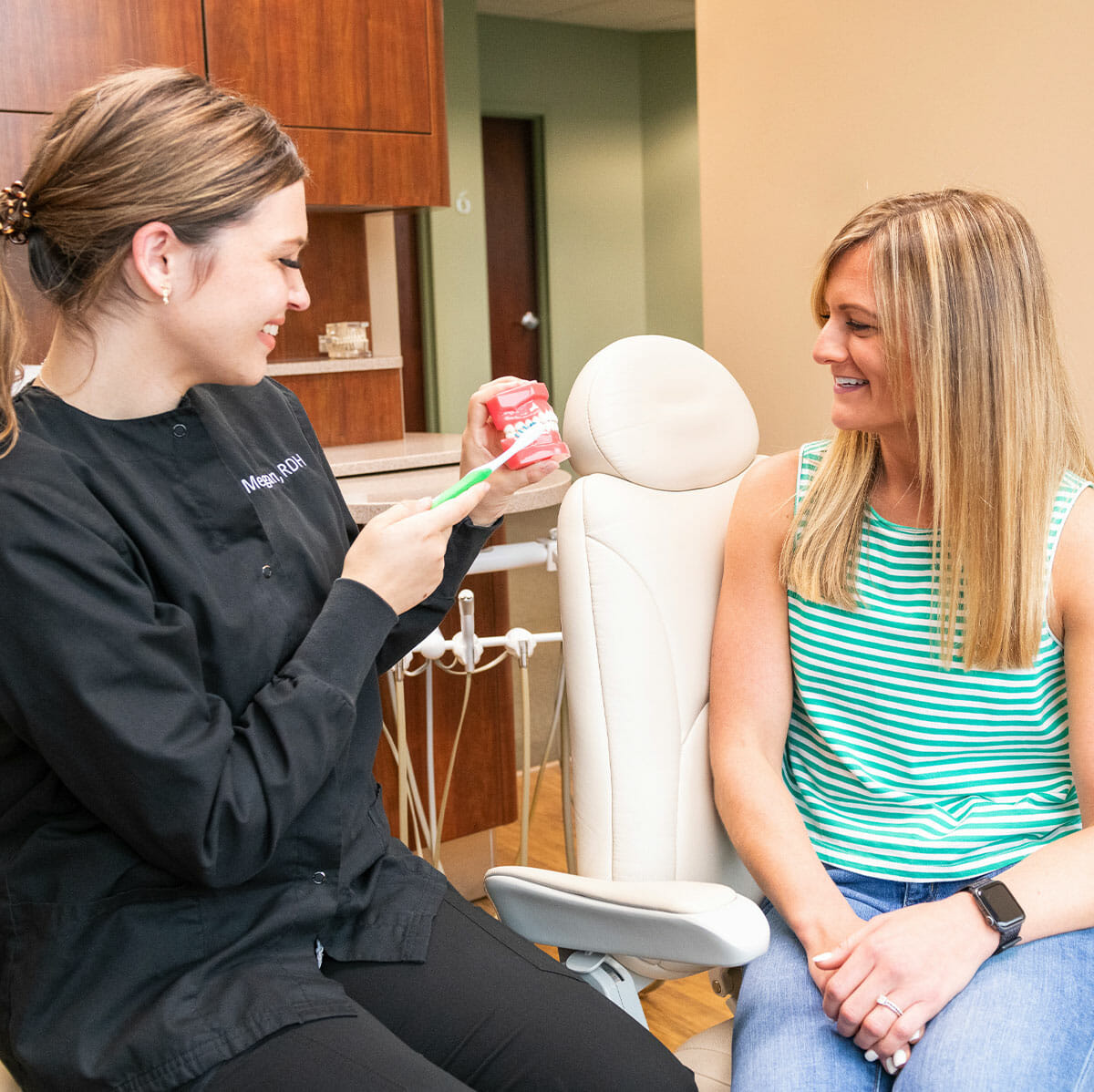Dental hygienist demonstrating proper teeth brushing technique to patient