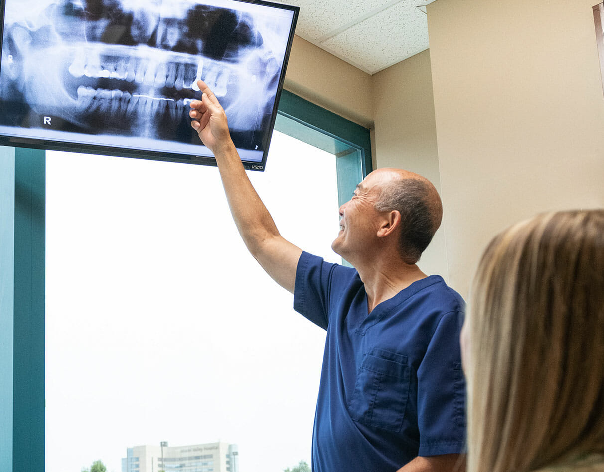 Dr. Sato pointing at x-ray of teeth on monitor